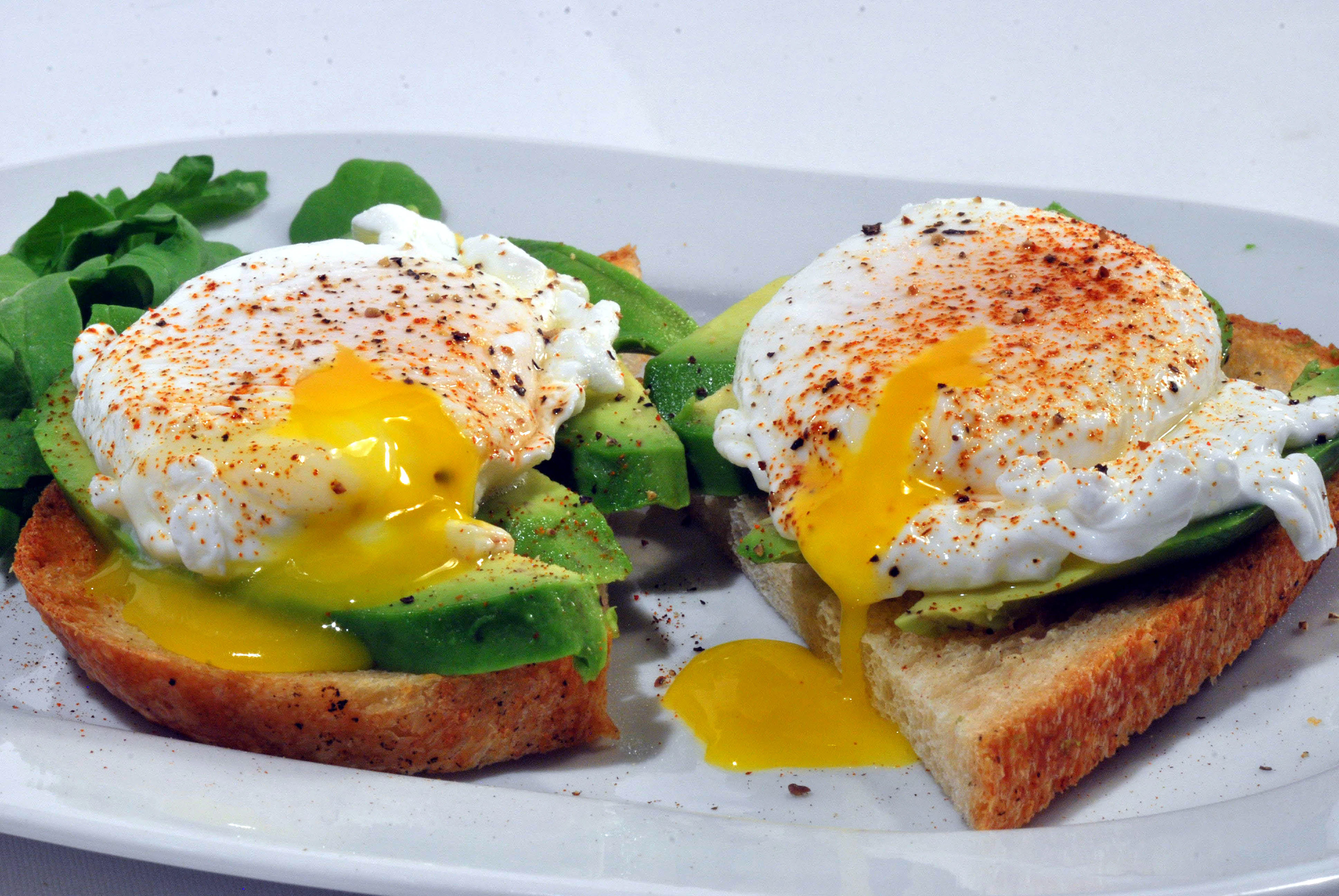 Tartine d’avocat surmontée de deux œufs au jaune coulant