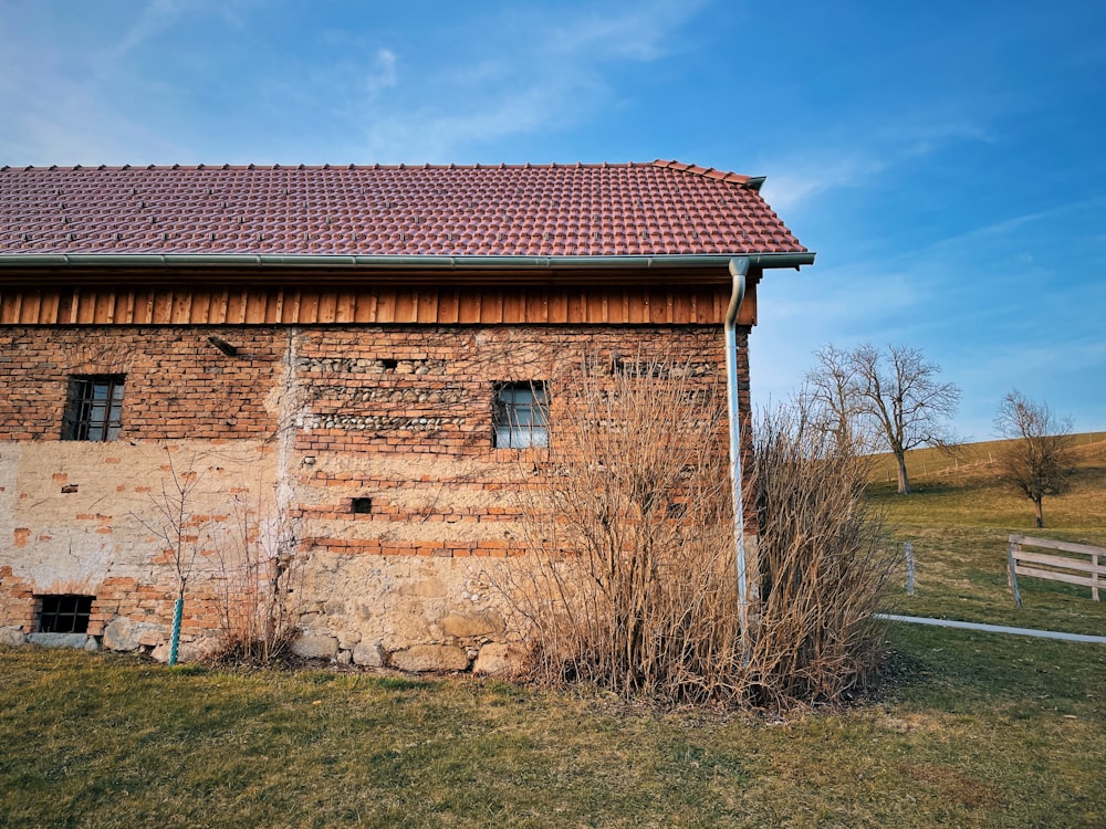 brown brick house near bare trees under blue sky during daytime