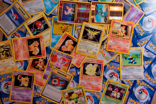 A collection of colorful Pokemon trading cards scattered across a flat surface