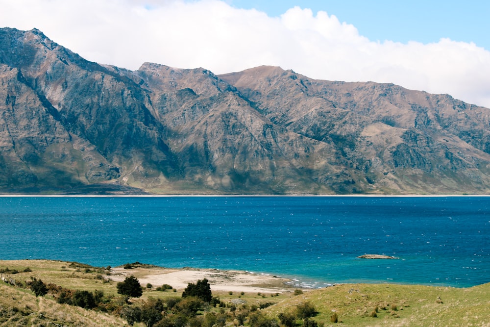 green and brown mountain beside blue sea during daytime