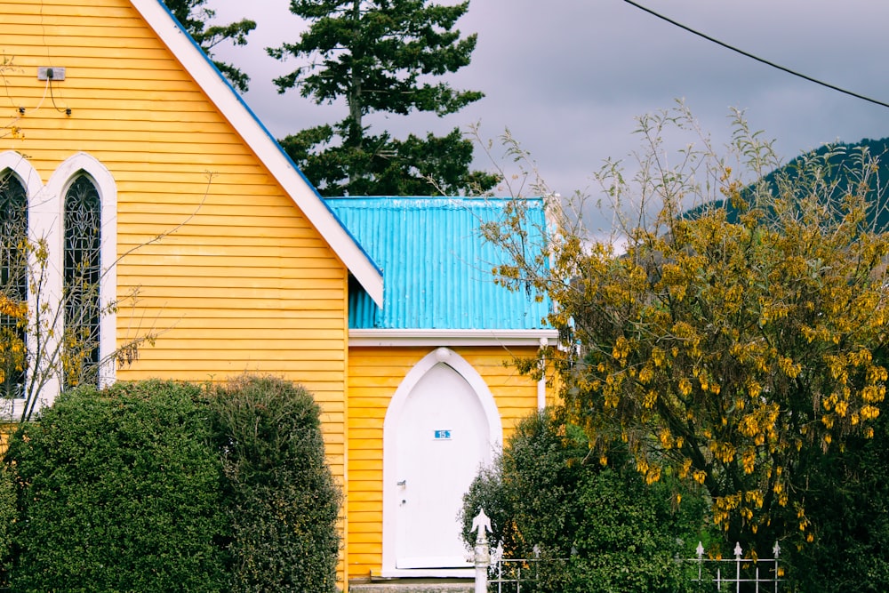 green and yellow wooden house near green trees under blue sky during daytime