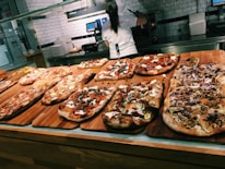 Close-up of a variety of colorful pizzas being served on wooden boards.