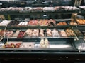 A well-lit pastry display case featuring an array of baked goods. The assortment includes croissants, cannoli, tarts, and various pastries decorated with powdered sugar, fruit, and chocolate. The shelves are organized with different kinds of sweets, creating an inviting and appetizing presentation.