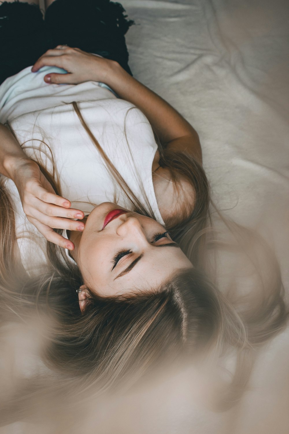 woman in white tank top lying on white bed