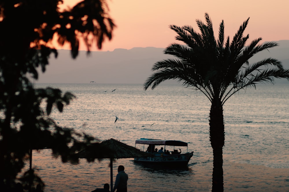 Silhouette von Menschen auf dem Boot auf See während des Sonnenuntergangs