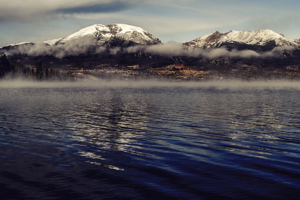 snow covered mountain near body of water during daytime