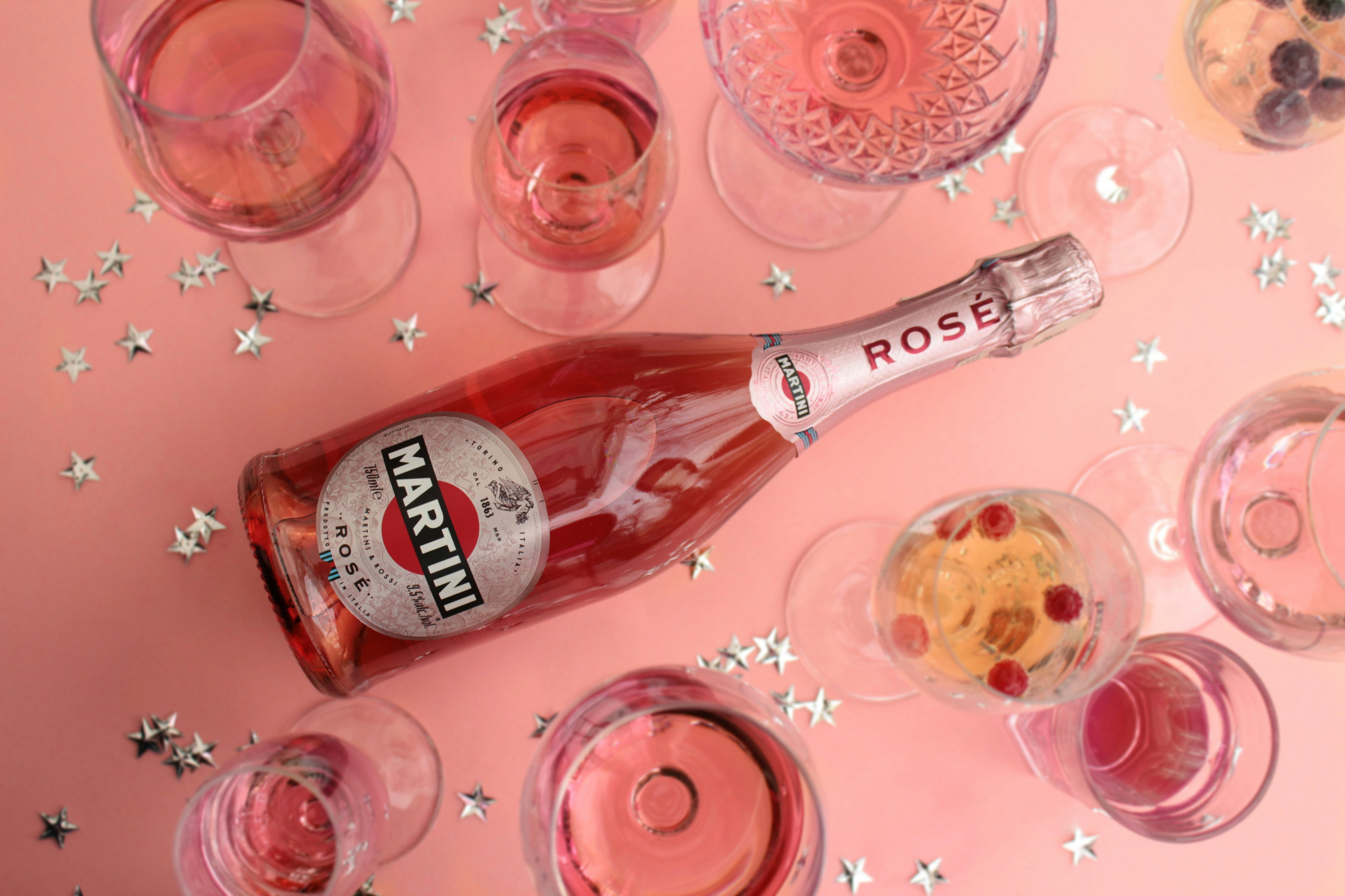 two red glass bottles on pink table