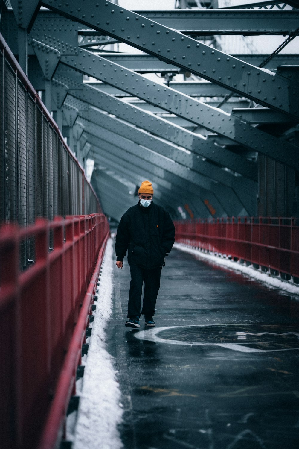 man in black jacket walking on red bridge