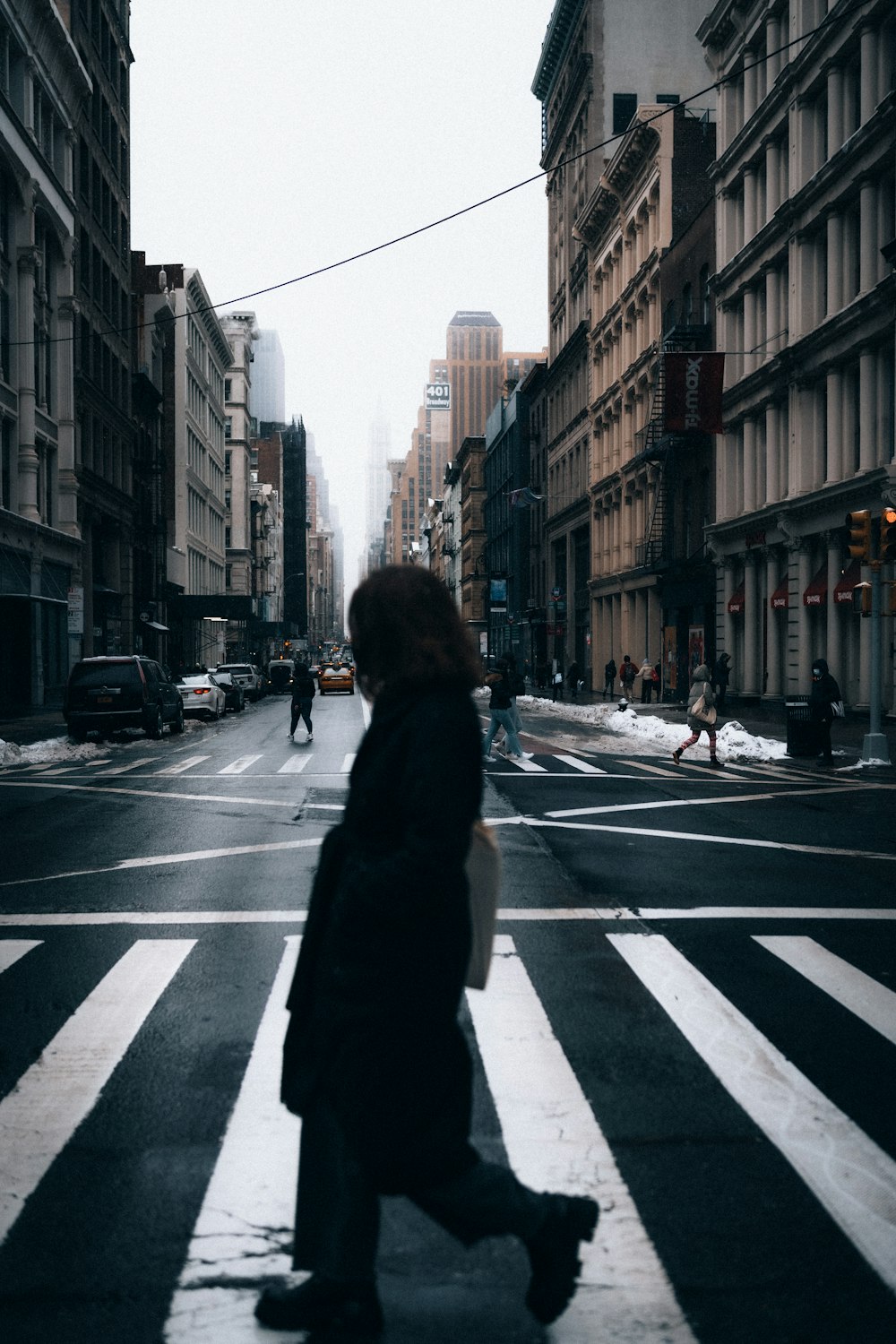 woman in black coat standing on pedestrian lane during daytime