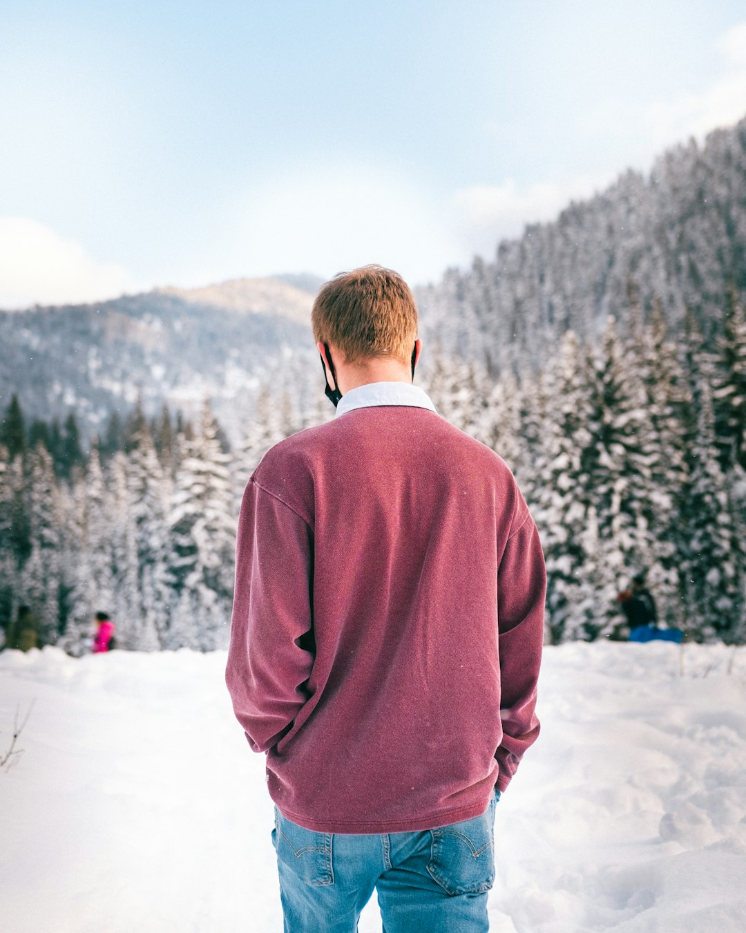man in red sweater standing on snow covered ground during daytime