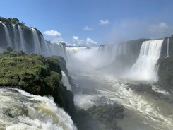 A breathtaking view of Iguazu Falls surrounded by lush greenery under a bright sky