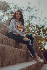 A laid-back scene of a man in a hoodie and sneakers, sitting on urban steps with a relaxed smile.