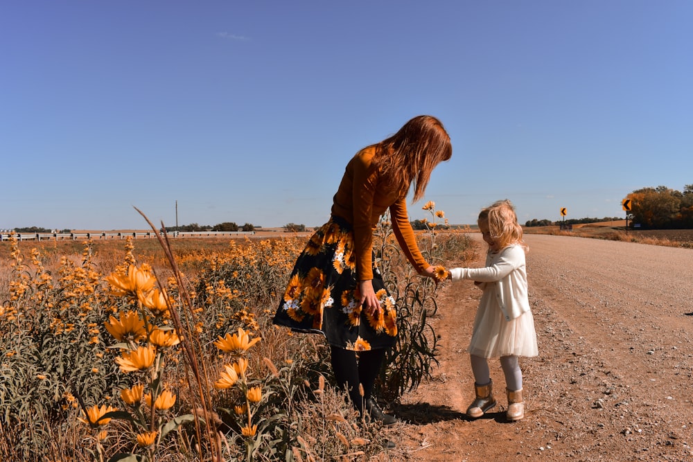 girl in white dress standing beside girl in white dress on brown grass field during daytime