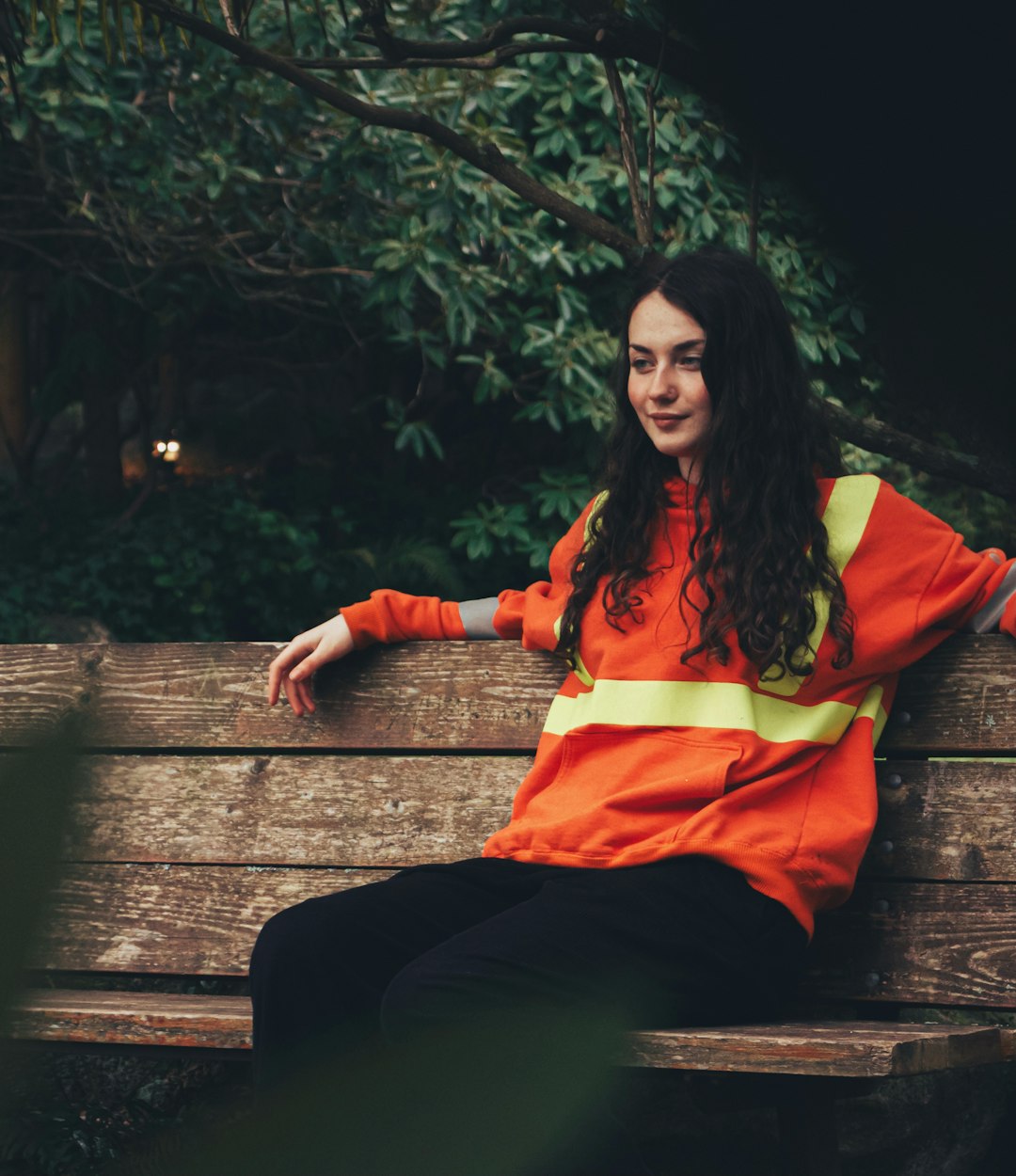 woman in red long sleeve shirt sitting on brown wooden bench