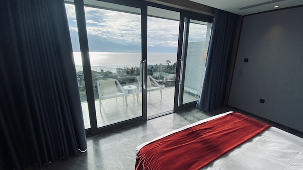 Spacious hotel room with a large bed and ocean view balcony.