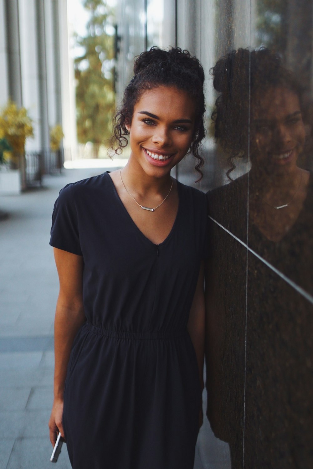 woman in black v neck t-shirt standing beside wall