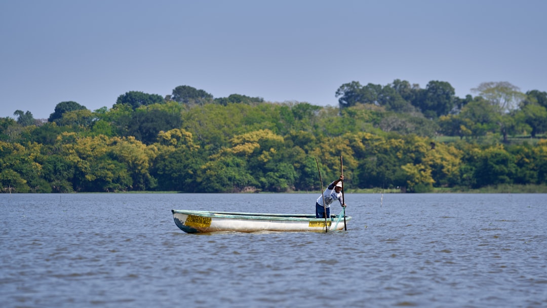 man in white and black boat on body of water during daytime