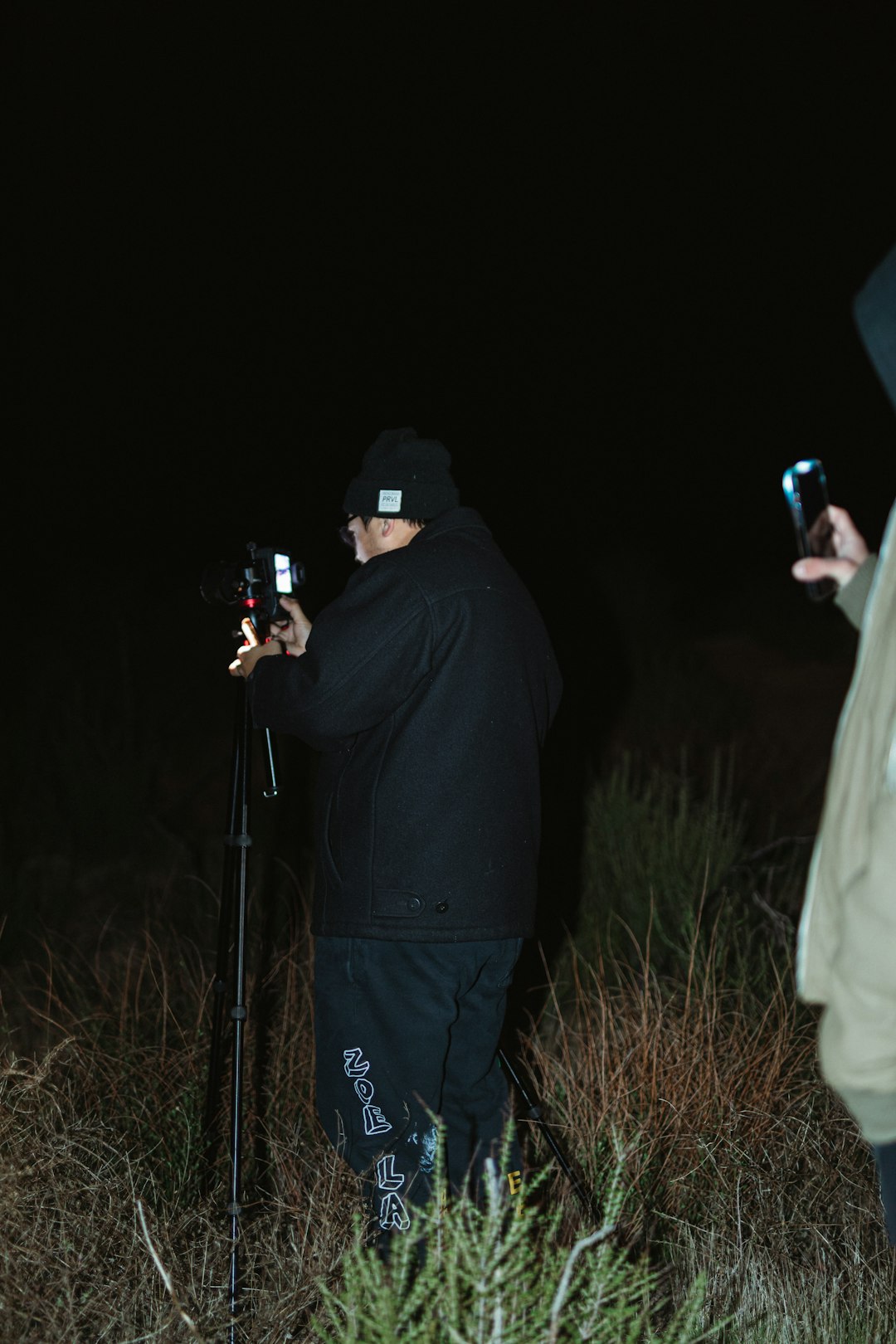 man in black hoodie holding black dslr camera