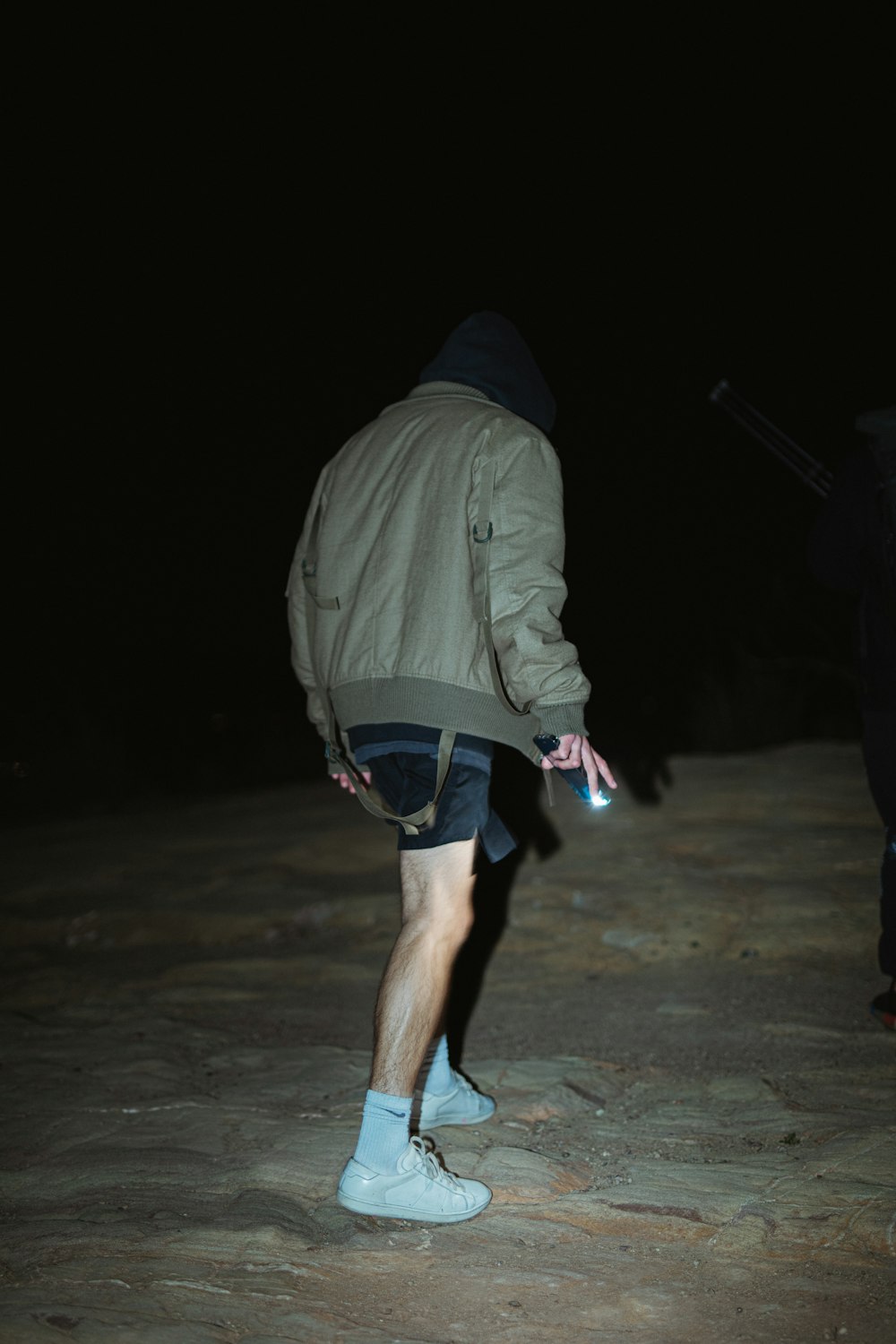 man in gray jacket walking on gray sand during nighttime