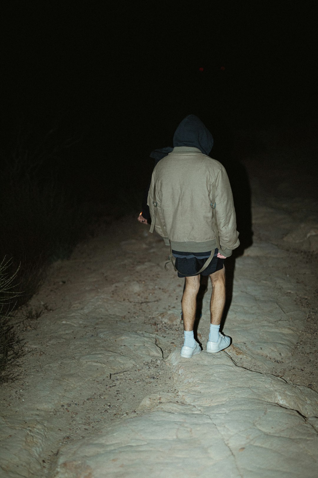 man in gray hoodie and blue shorts standing on gray sand during nighttime