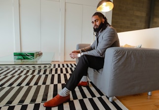 A well-groomed man smiling in the lounge with tobacco brown and kelly green accents.