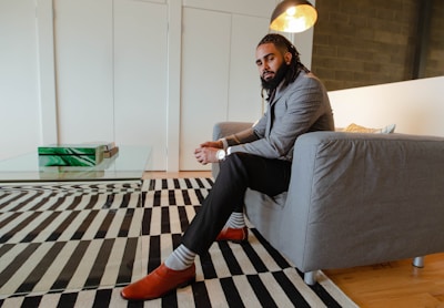 A well-groomed man smiling in the lounge with tobacco brown and kelly green accents.