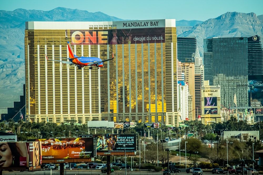 red and white airplane on mid air near city buildings during daytime