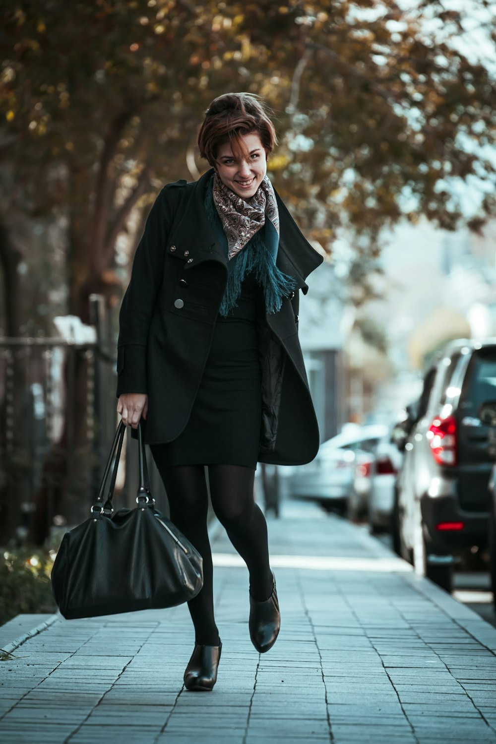 woman in black coat holding black leather handbag