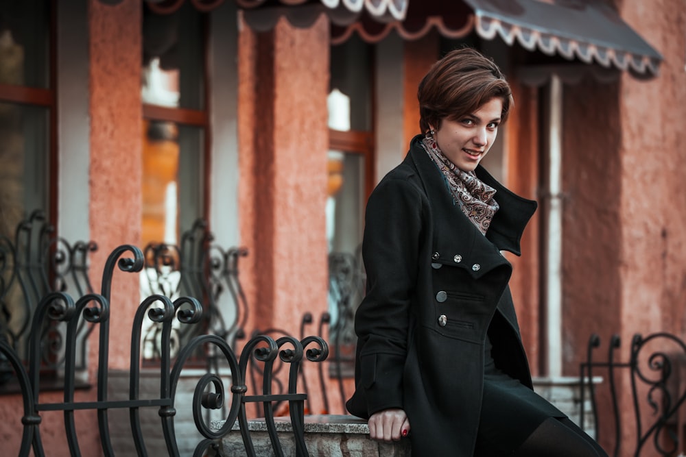 woman in black coat sitting on brown wooden bench