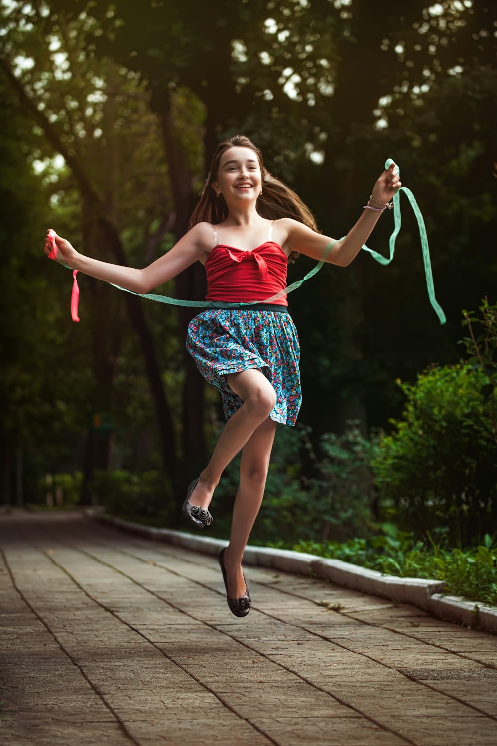 woman in pink tank top and blue skirt standing on gray concrete pathway during daytime