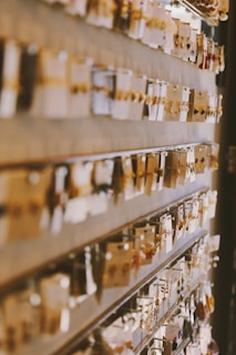 A store display featuring numerous pairs of dangling earrings arranged on hooks, with each pair attached to its own card. The background is blurred, highlighting the focus on the jewelry. The scene is warmly lit, enhancing the golden and metallic tones of the earrings.