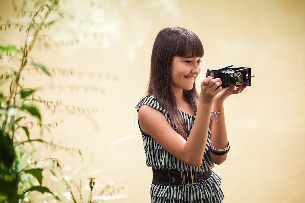 woman in black and white stripe dress holding black camera