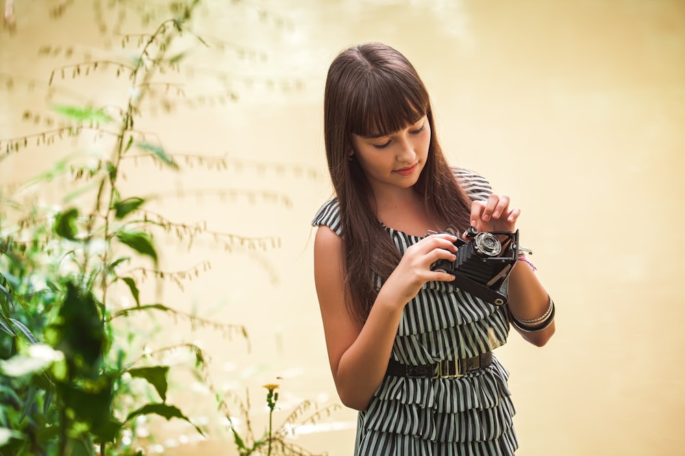 woman in black and white stripe tank dress holding black dslr camera