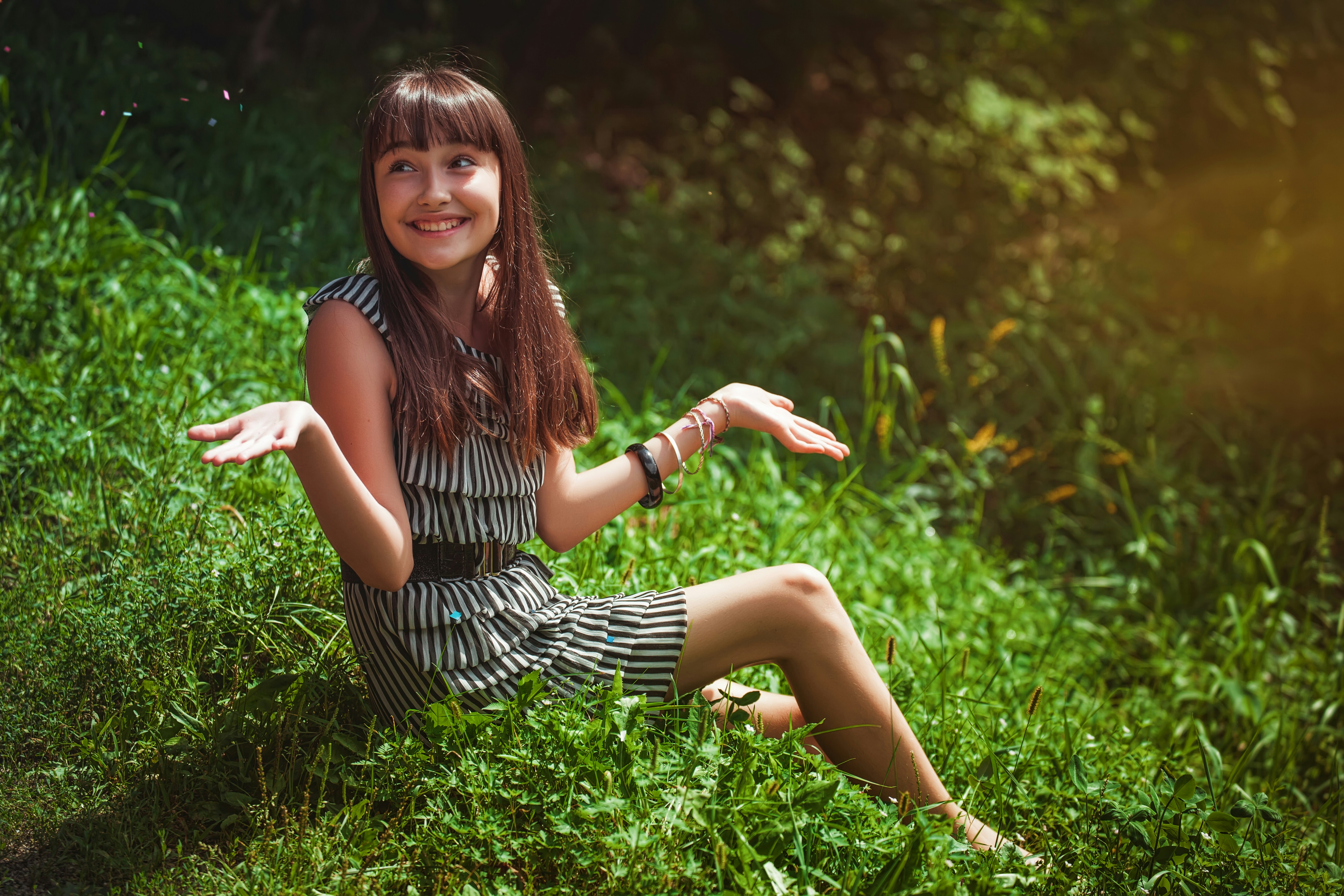 woman in black and white striped dress sitting on green grass during daytime