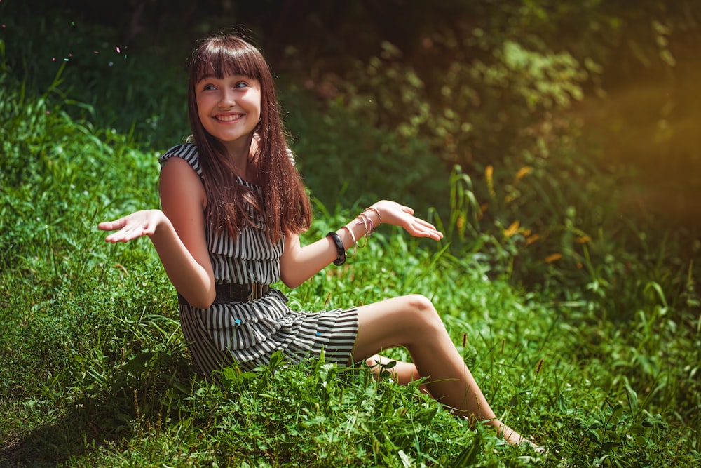 woman in black and white striped dress sitting on green grass during daytime