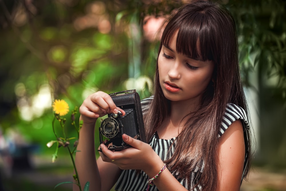 woman in black and white striped shirt holding black camera