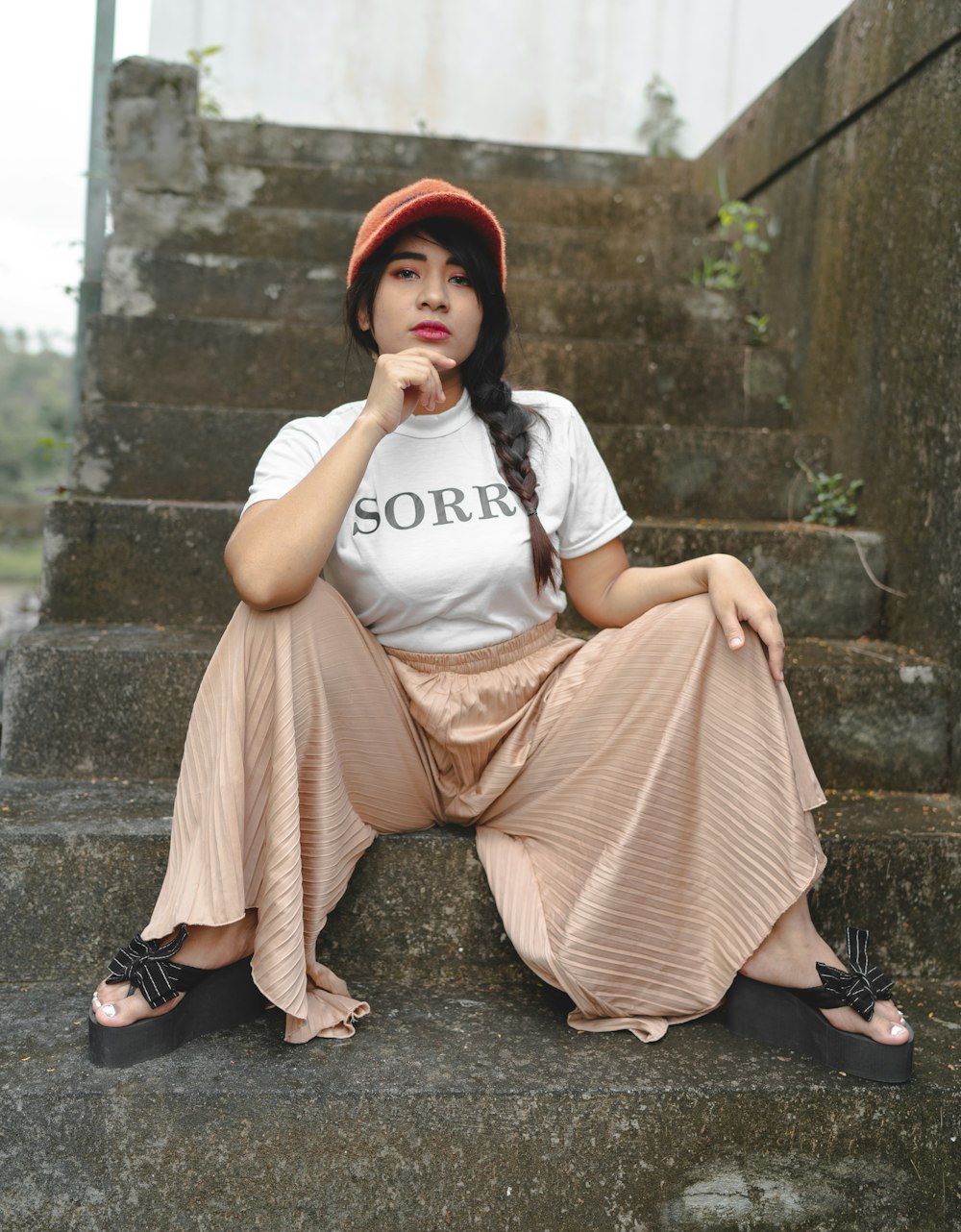 woman in white t-shirt and pink skirt sitting on concrete stairs