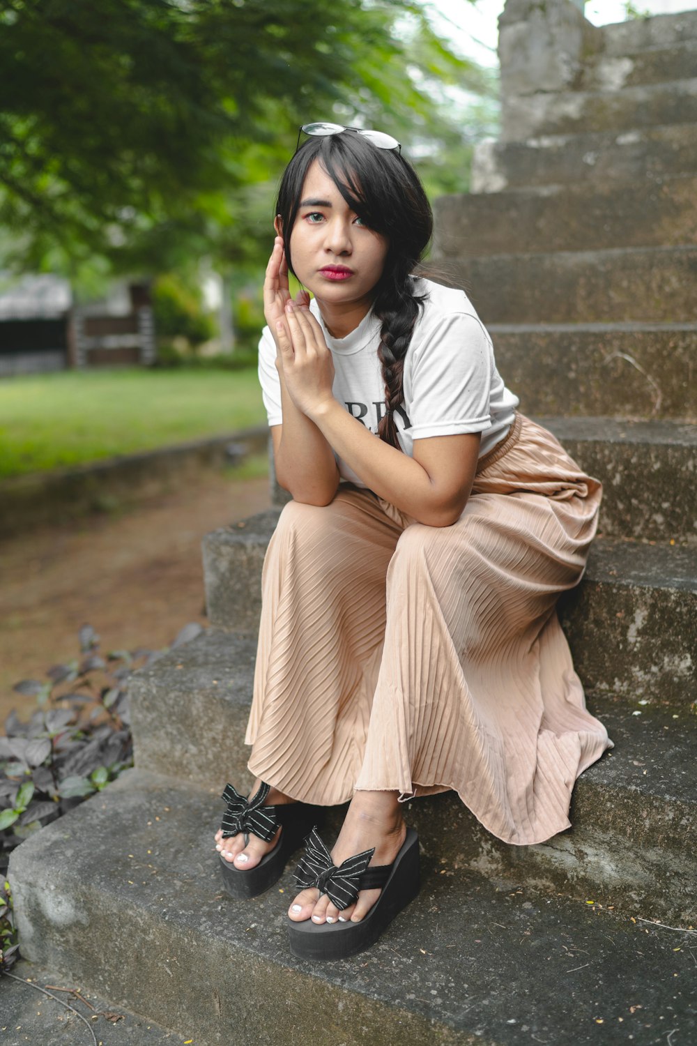 woman in white shirt and black skirt sitting on concrete stairs