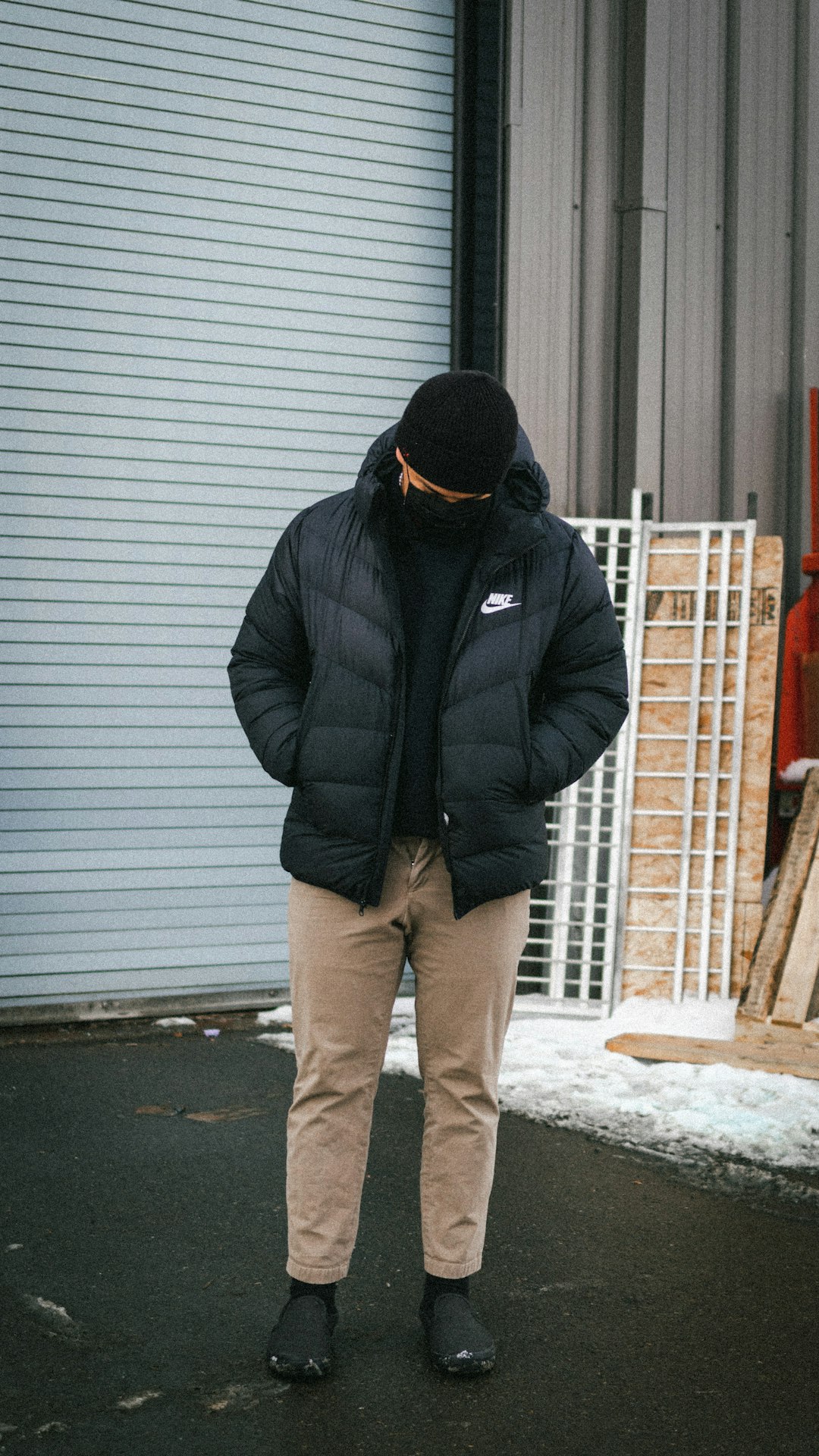 man in black jacket and brown pants standing on snow covered ground