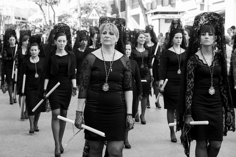 Foto in scala di grigi di donna in abito nero in piedi sulla strada