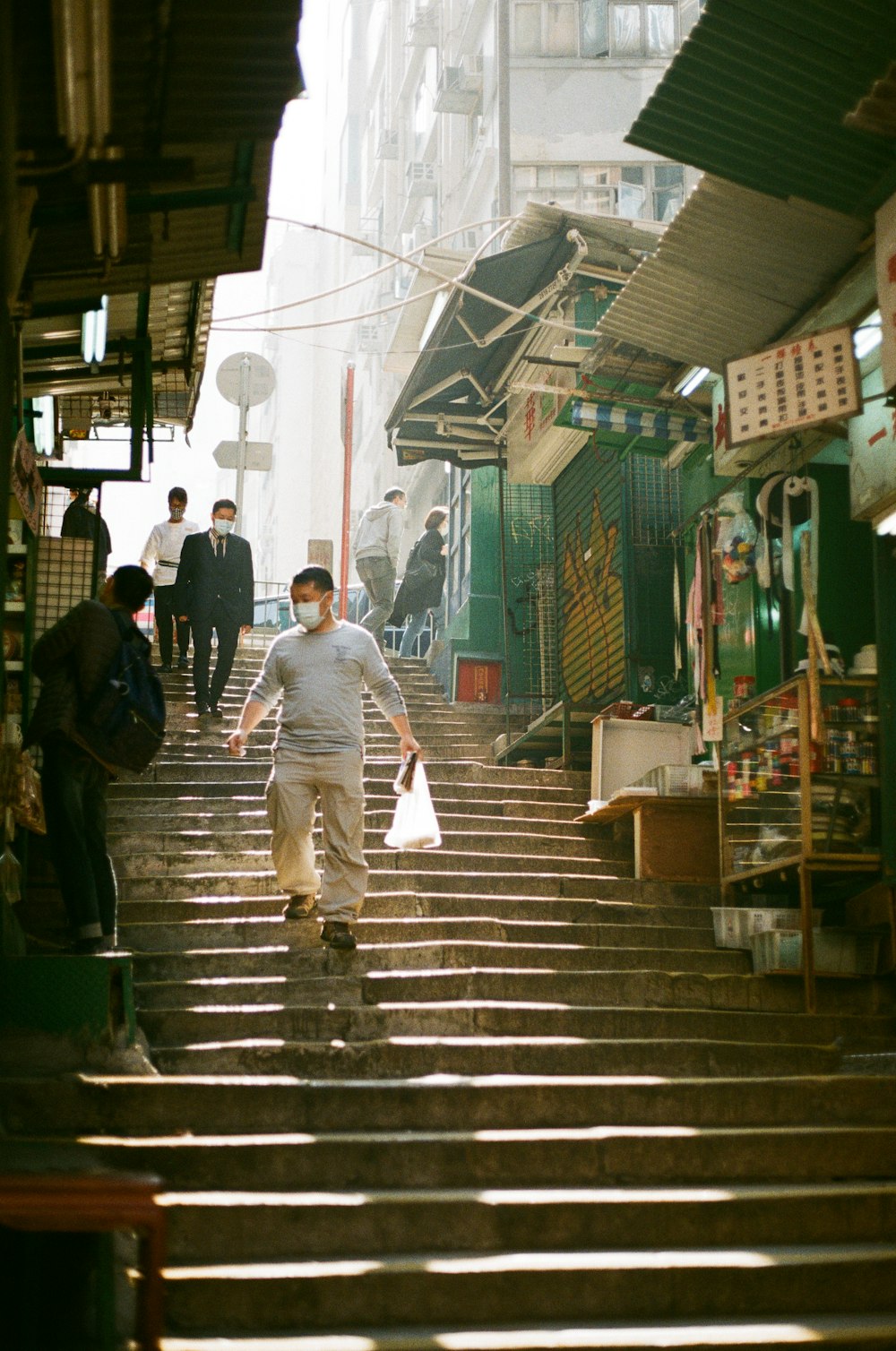 man in gray dress shirt walking on sidewalk during daytime