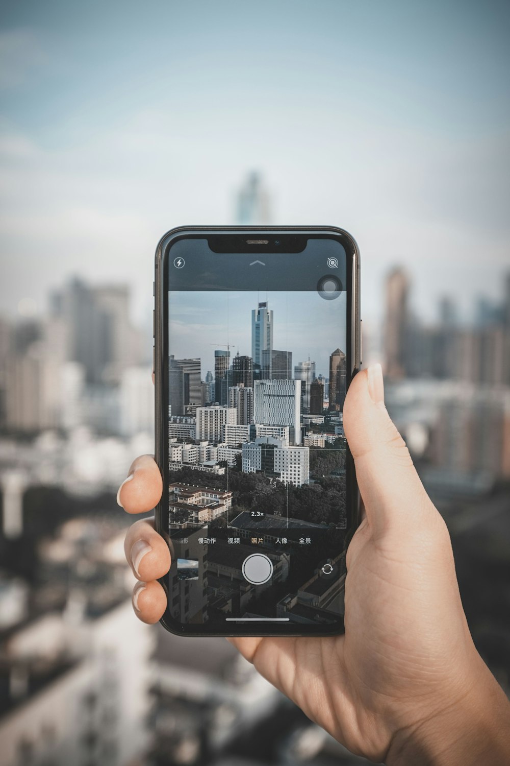 person holding iphone taking photo of city buildings during daytime