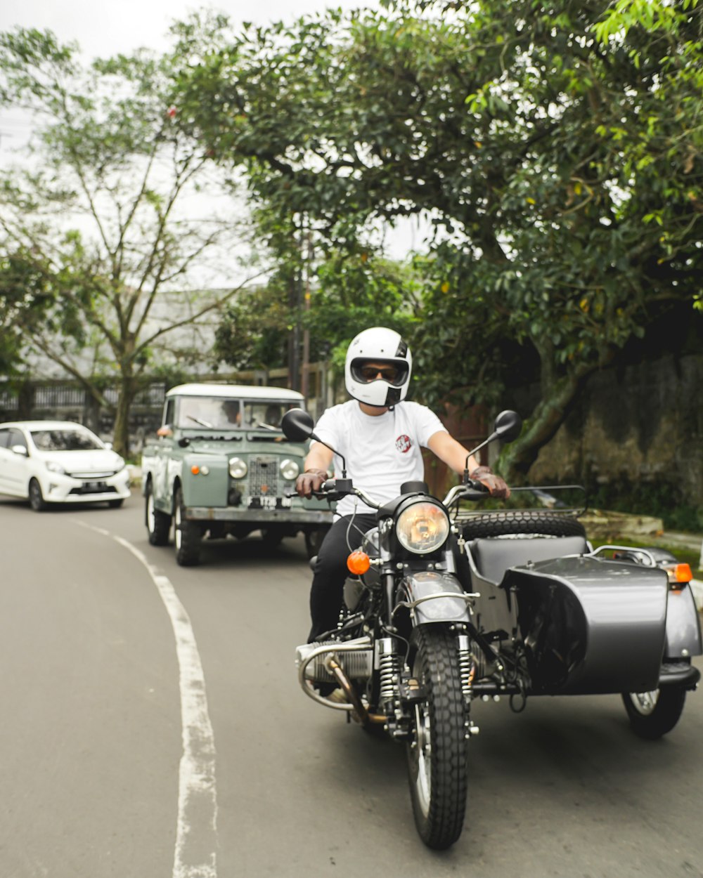 昼間の道路でバイクに乗る白いヘルメットの男