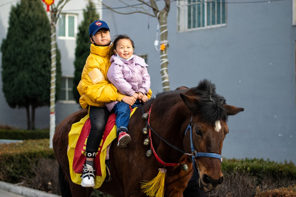 girl in yellow jacket riding brown horse during daytime