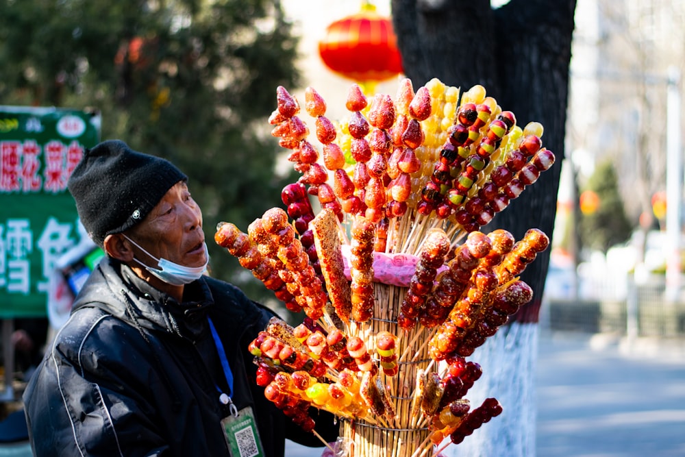 man in blue jacket holding yellow and red flower bouquet