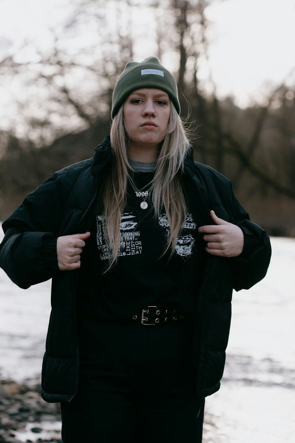 woman in black jacket and green cap standing on snow covered ground during daytime