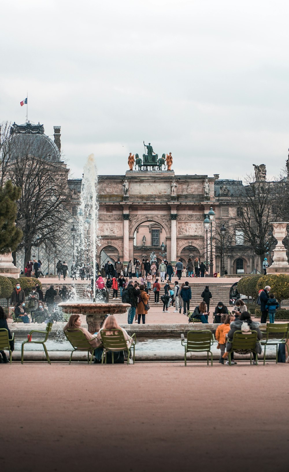 people sitting on bench near fountain during daytime