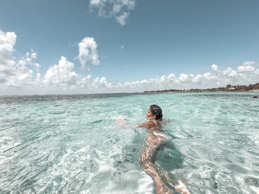 woman in red bikini swimming in the sea during daytime