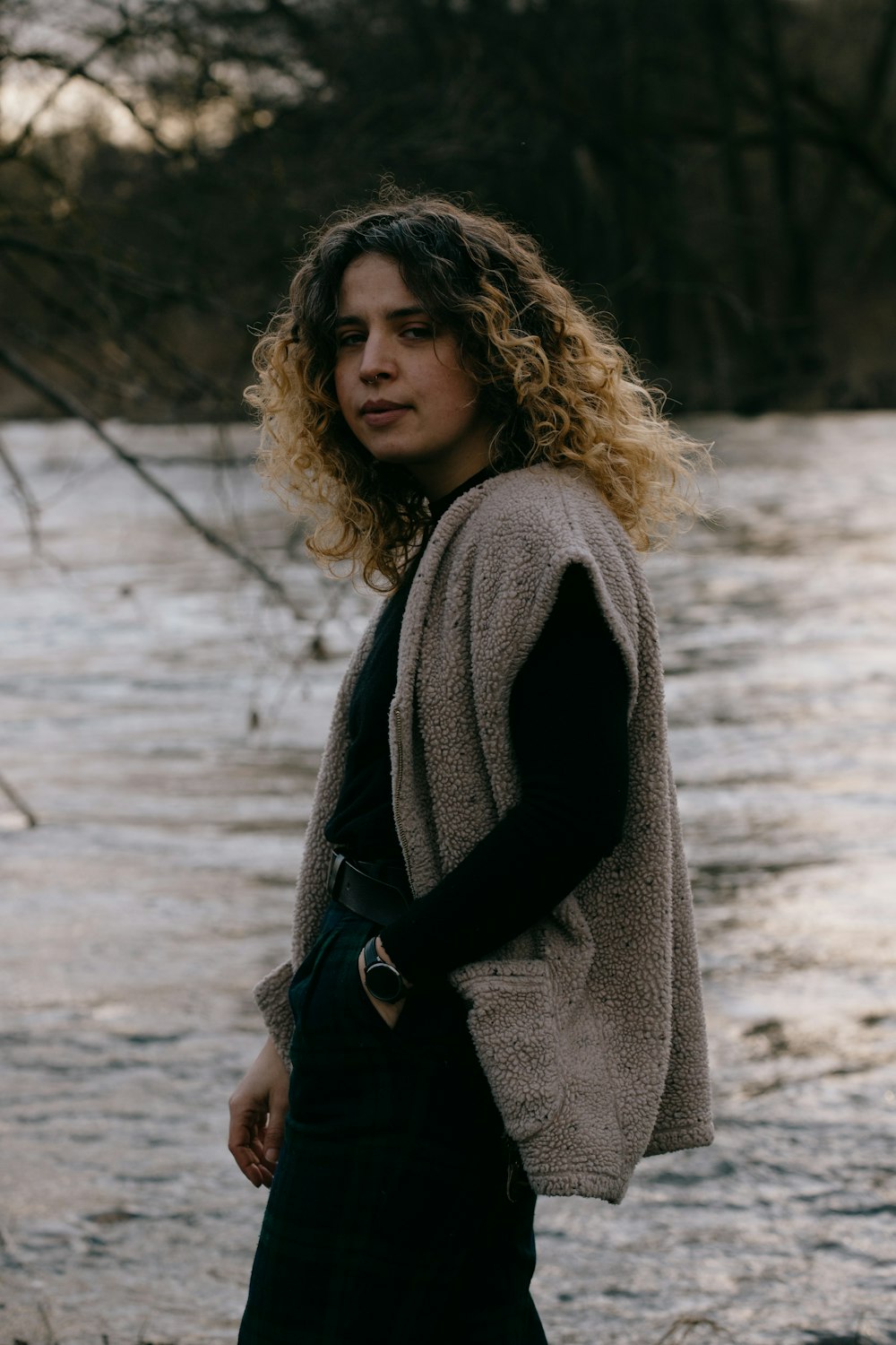 woman in gray coat standing on snow covered ground during daytime