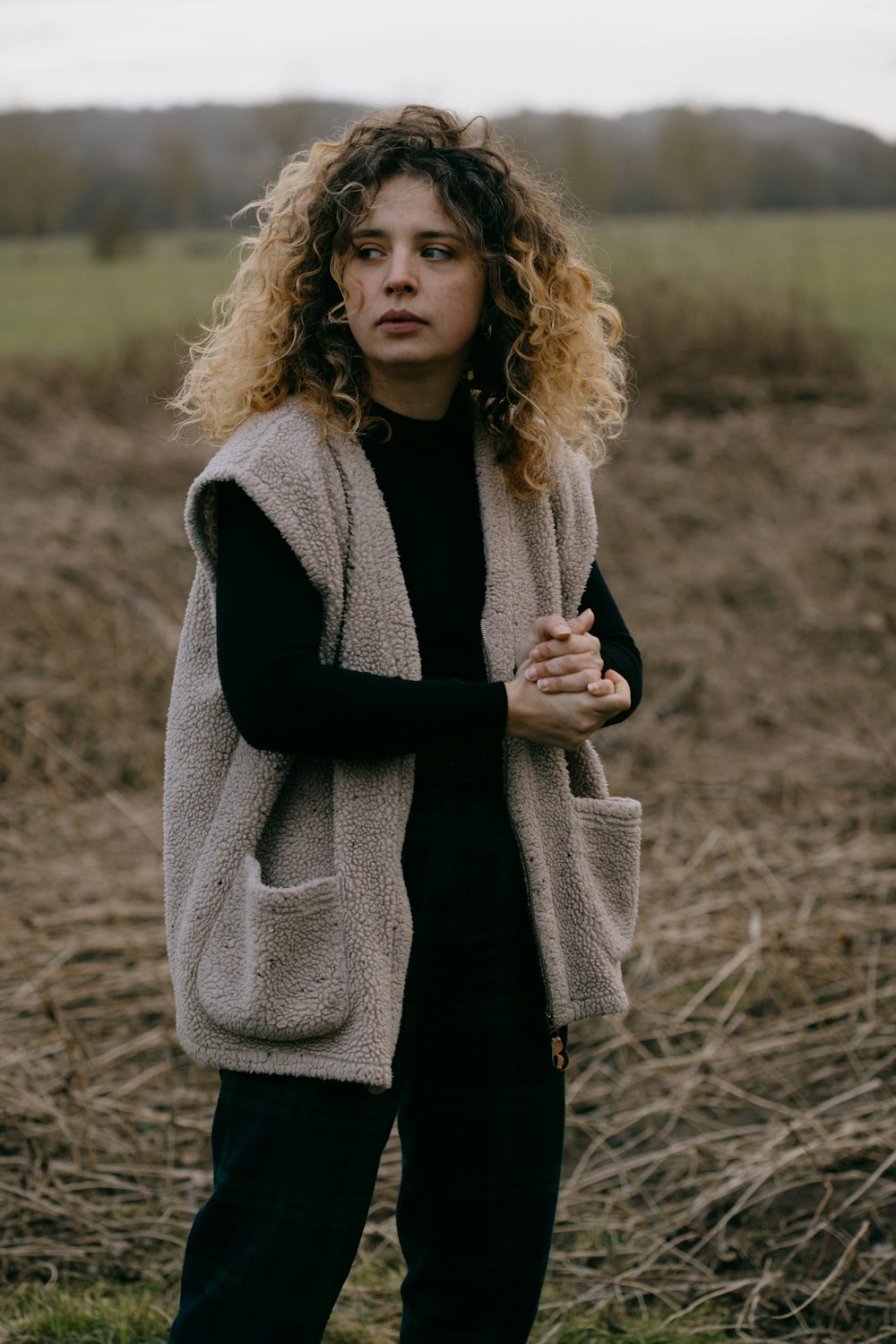 woman in black coat standing on brown grass field during daytime